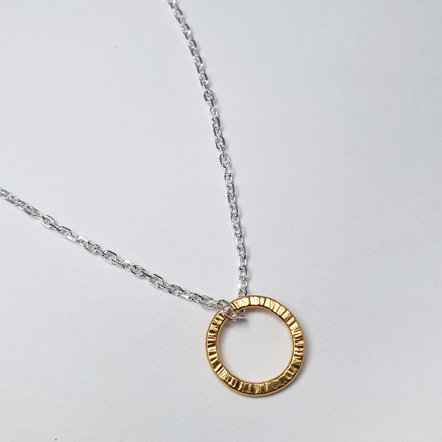 Yellow gold vermeil circular pendant necklace worn on the body.
