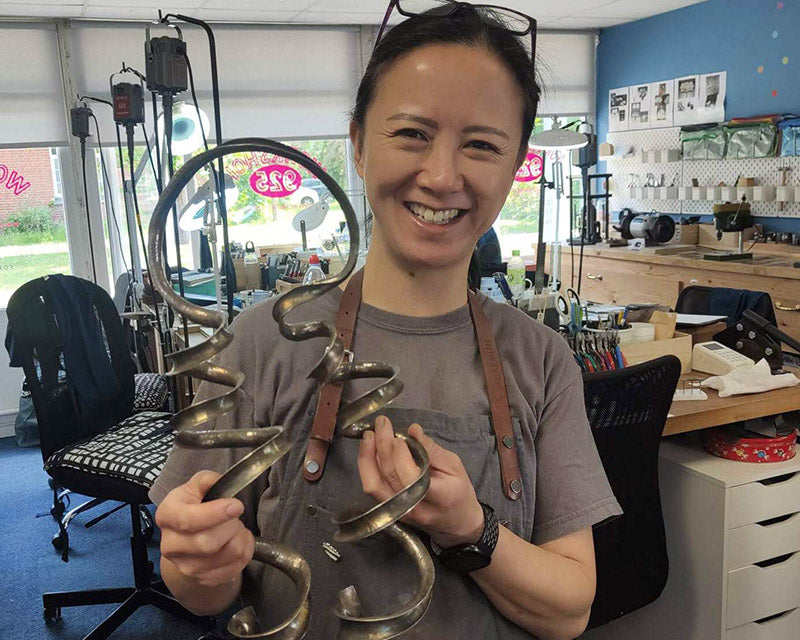 Silversmith Jenny Holdsworth holding up an item of silver to be polished in a polishing and finishing course run by Stephen Goldsmith, AKA The Polishing Guru