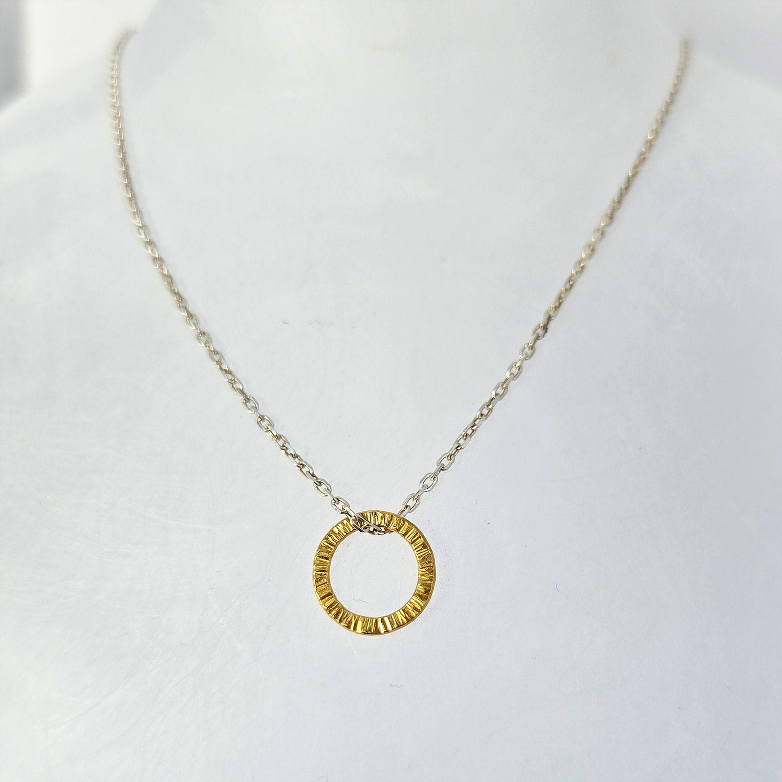 Sterling silver circular pendant necklace with hand-textured surface, finished in yellow gold vermeil.