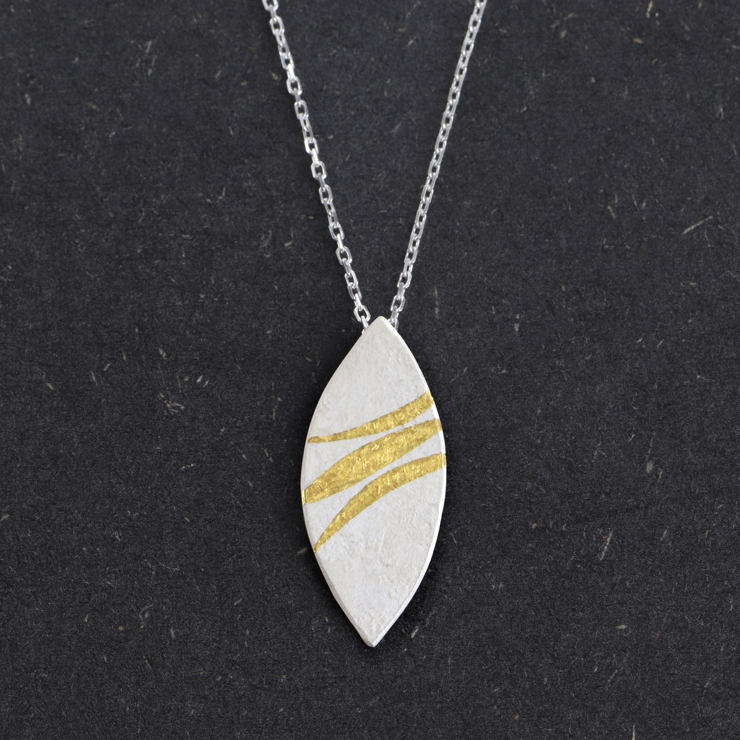 Handcrafted sterling silver marquise pendant with 24ct gold Keum-Boo ribbons by Jenny Holdsworth
