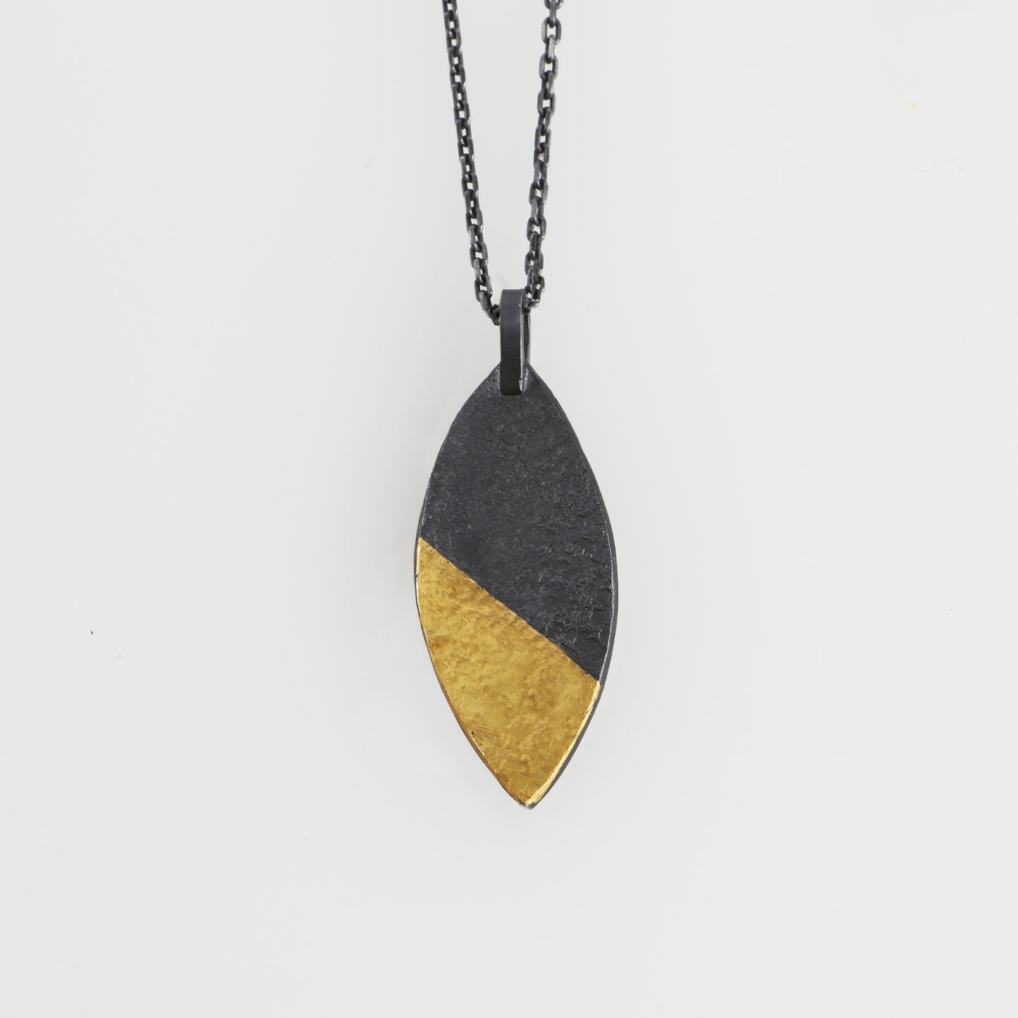 A marquise shaped pendant with a golden tip, hand made by Jenny Holdsworth