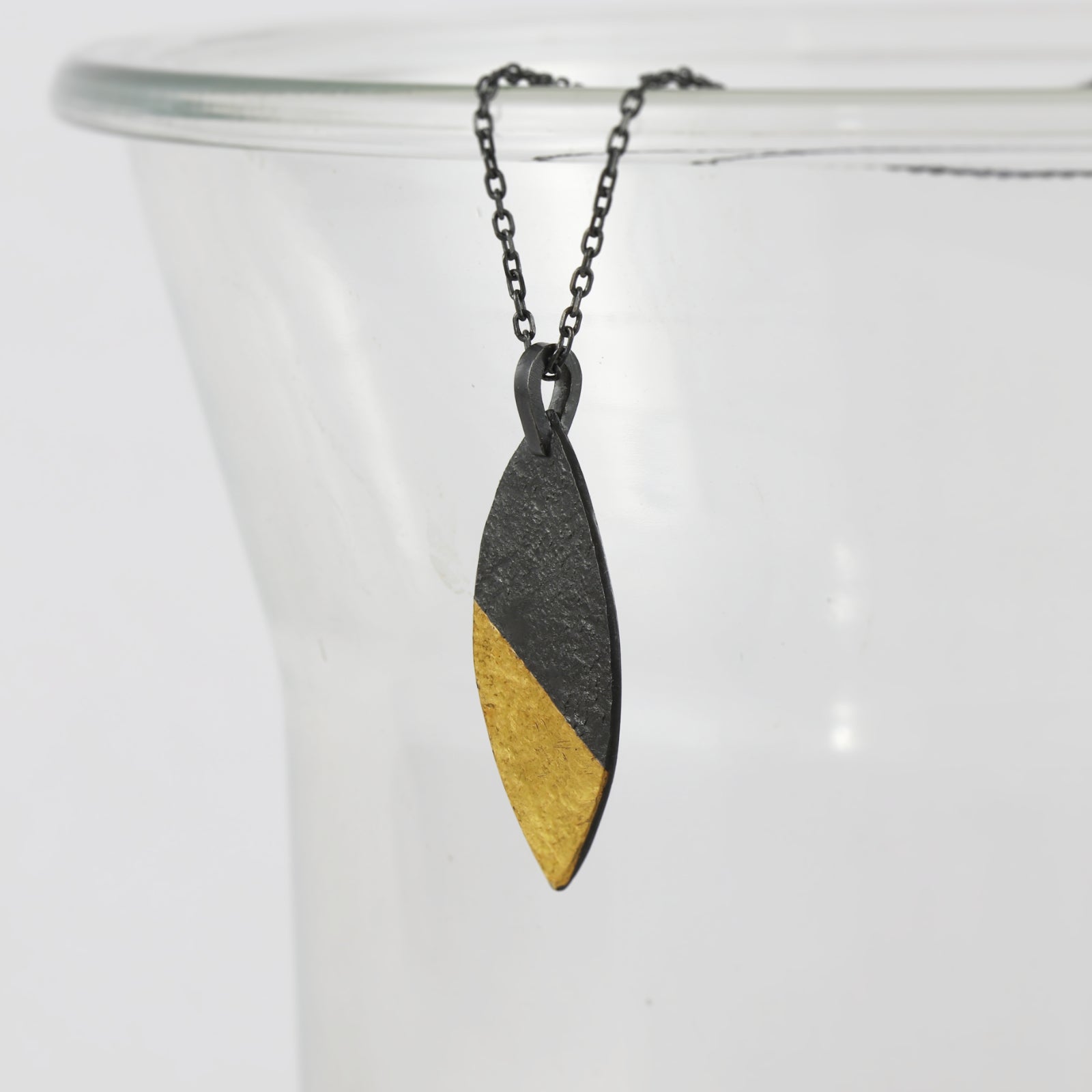 A marquise pendant in oxidised silver with a golden tip, hand made by Jenny Holdsworth