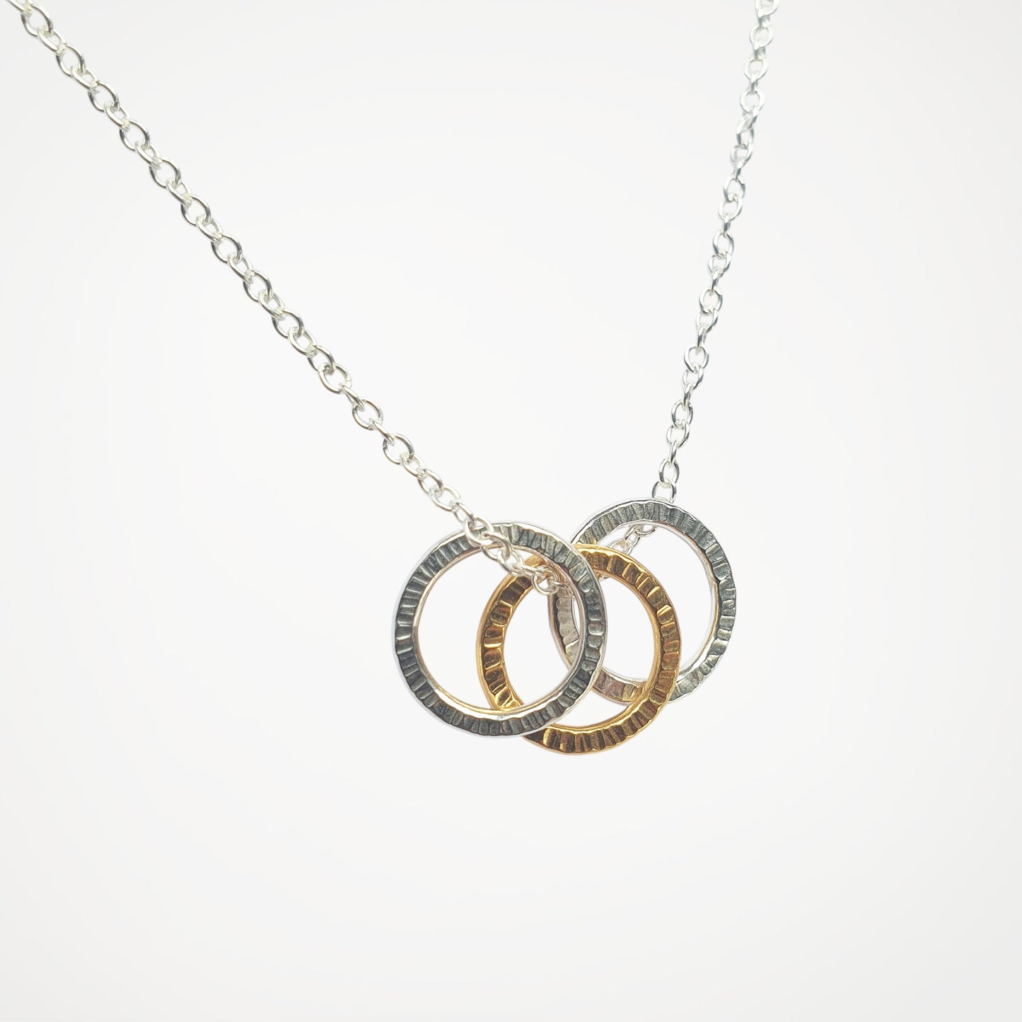 Necklace with three interlocking rings in silver and gold on a white background