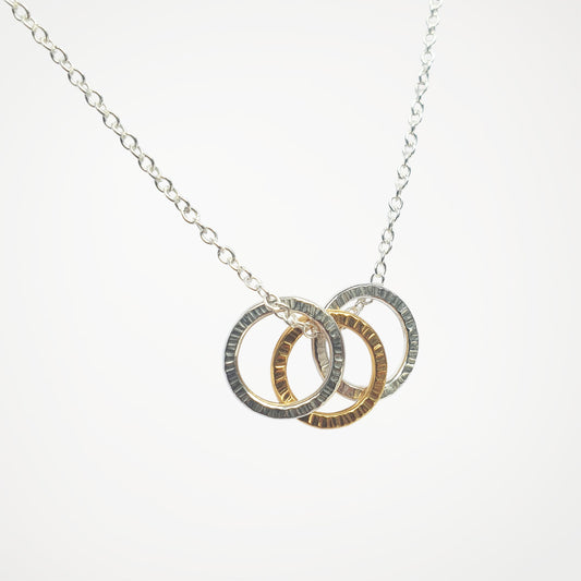 Necklace with three interlocking rings in silver and gold on a white background