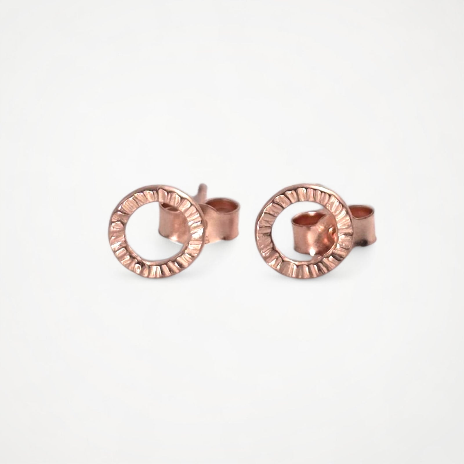 Pair of rose gold stud earrings on a white background