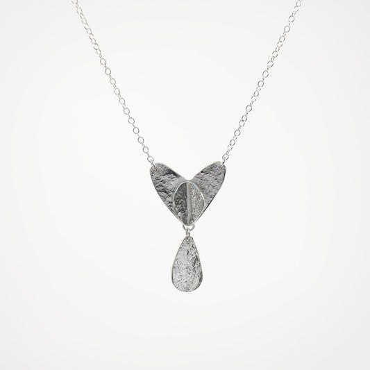 Silver necklace with a heart-shaped pendant and teardrop charm on a white background