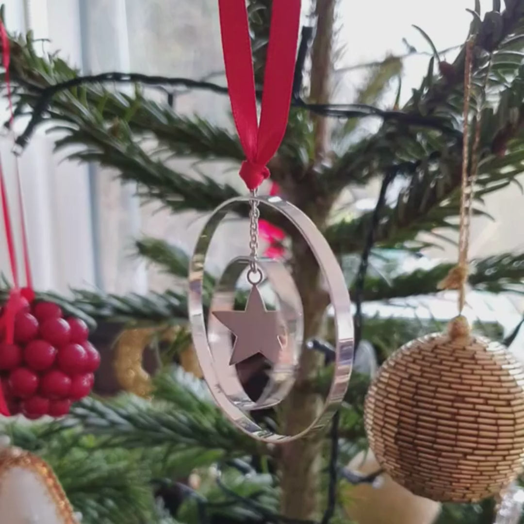 A sterling silver Christmas Tree decoration hand made by Jenny Holdsworth. With two concentric swinging rings and a star at its centre.