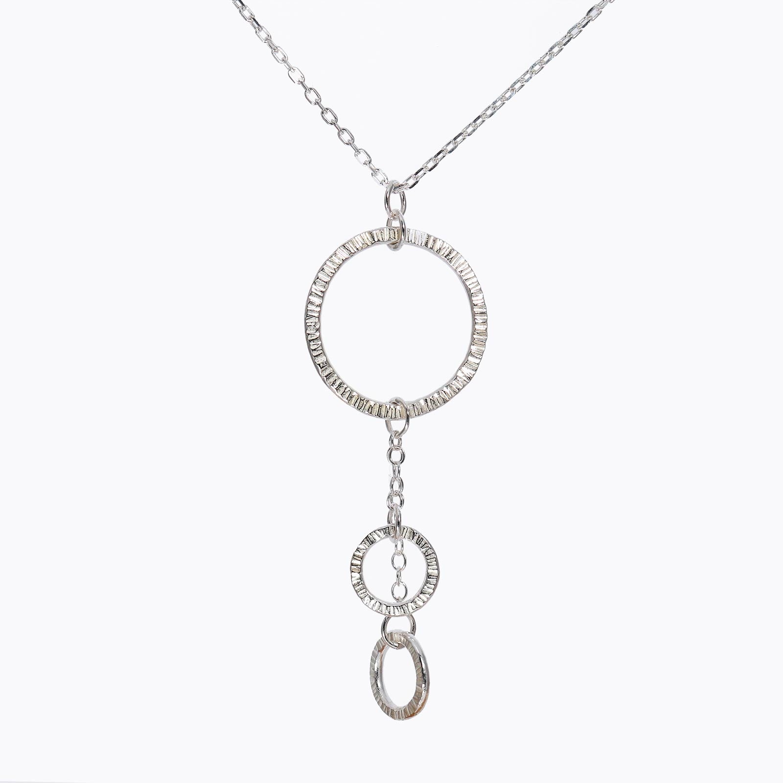 A silver necklace with a central circular pendant and two smaller textured circles, suspended from a larger circle.